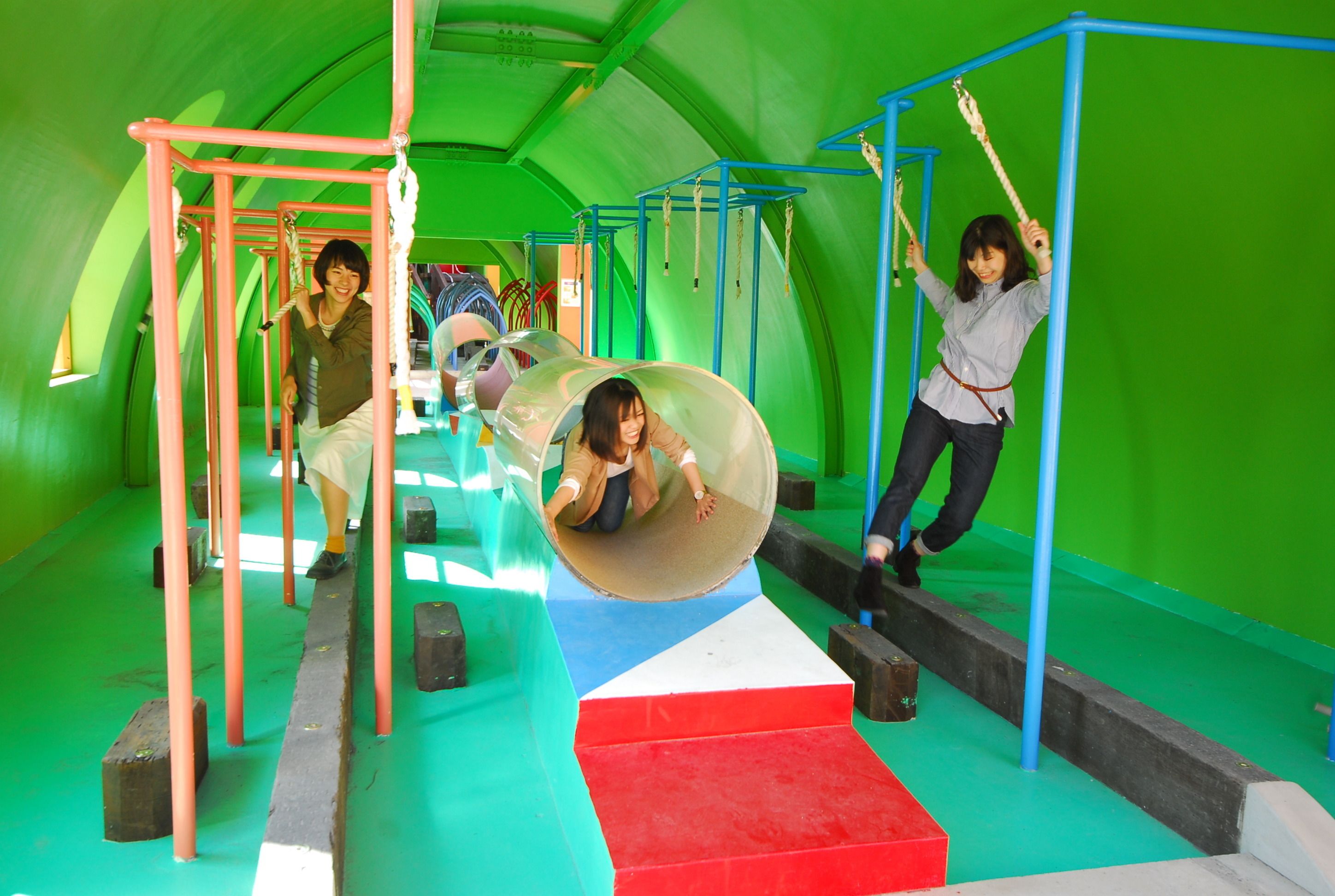 A play area with a transparent ball pit, climbing structures, and a slide.