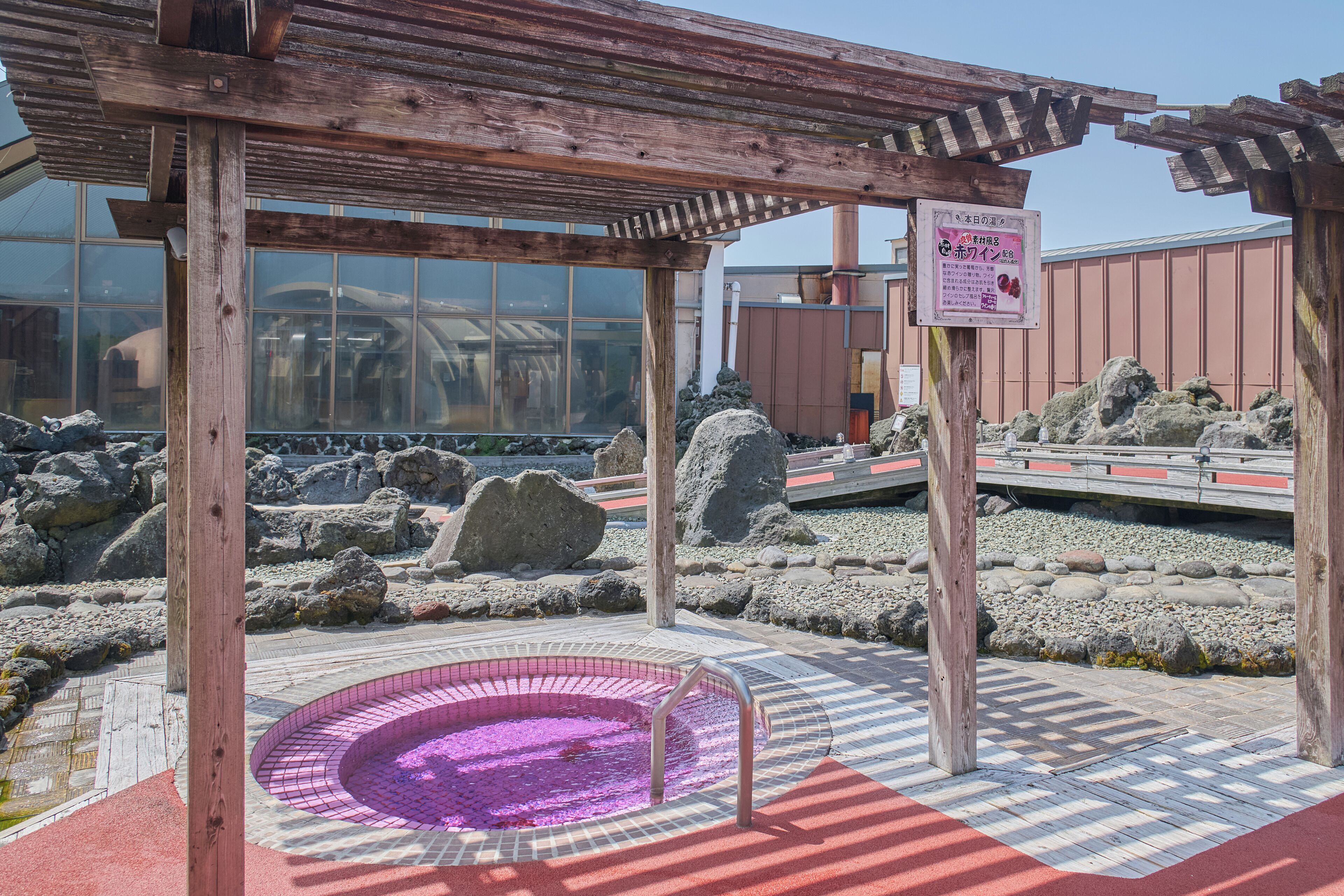 A wooden pavilion with a pool area, surrounded by rocks and a wooden deck.