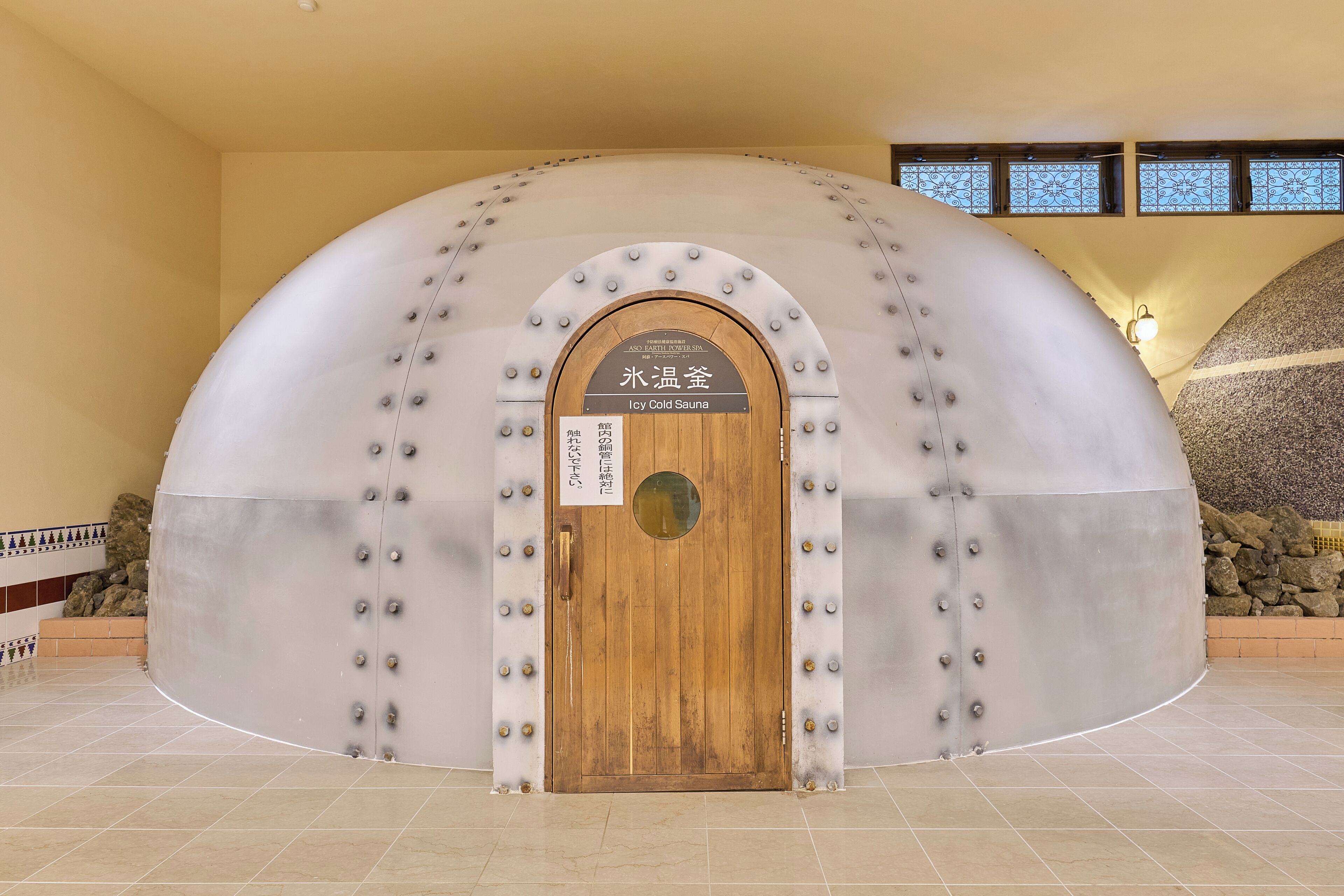 Uma estrutura metálica arqueada com uma porta de madeira identificada como "Icy Cold Sauna".