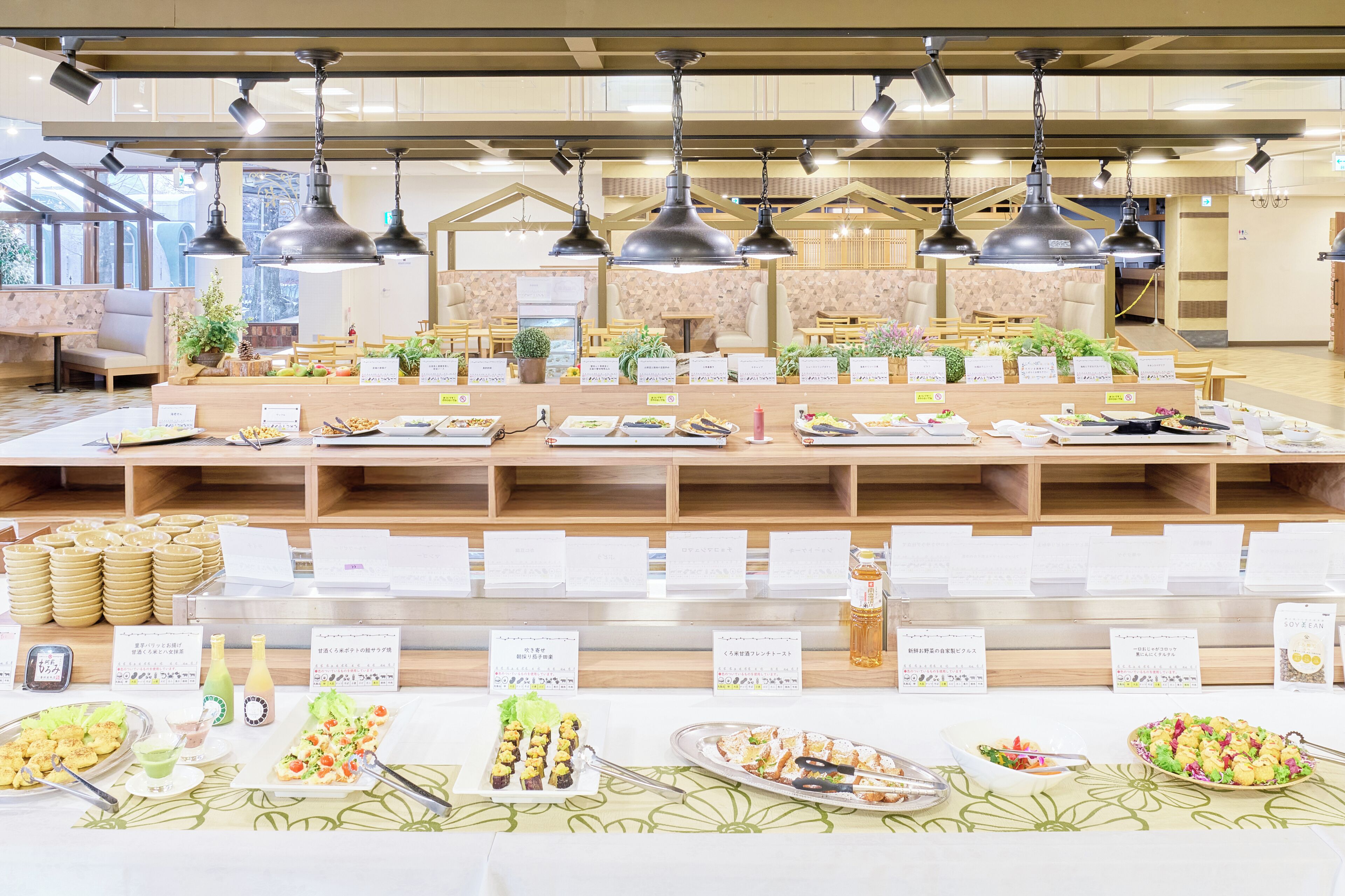 A buffet area with various food stations, wooden tables, and hanging pendant lights.