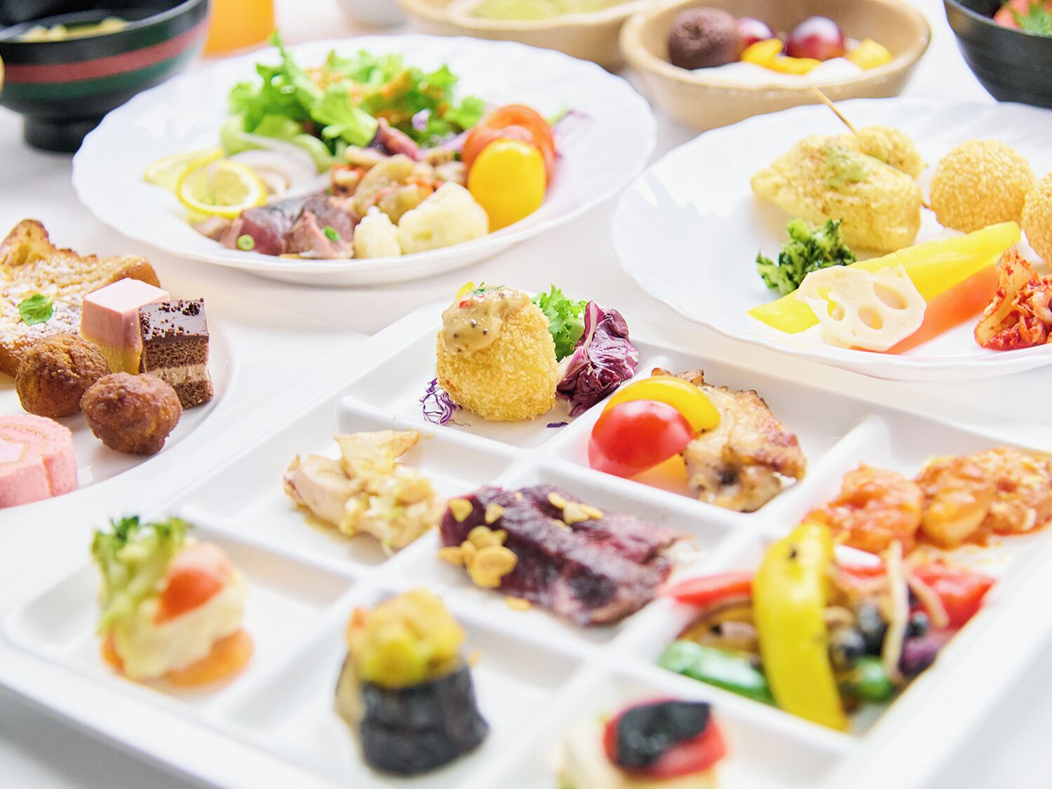 Variedad de platos en una mesa de buffet, incluyendo ensaladas, carnes y postres.