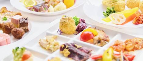 Variedad de platos en una mesa de buffet, incluyendo ensaladas, carnes y postres.