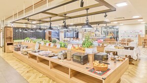 Montaje de bufé con diversos alimentos y aparatos, mostradores de madera y luces colgantes.