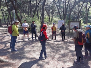A group of people standing in a forested area with a signboard in the background. - Good Moments sharehouse (Incheon)