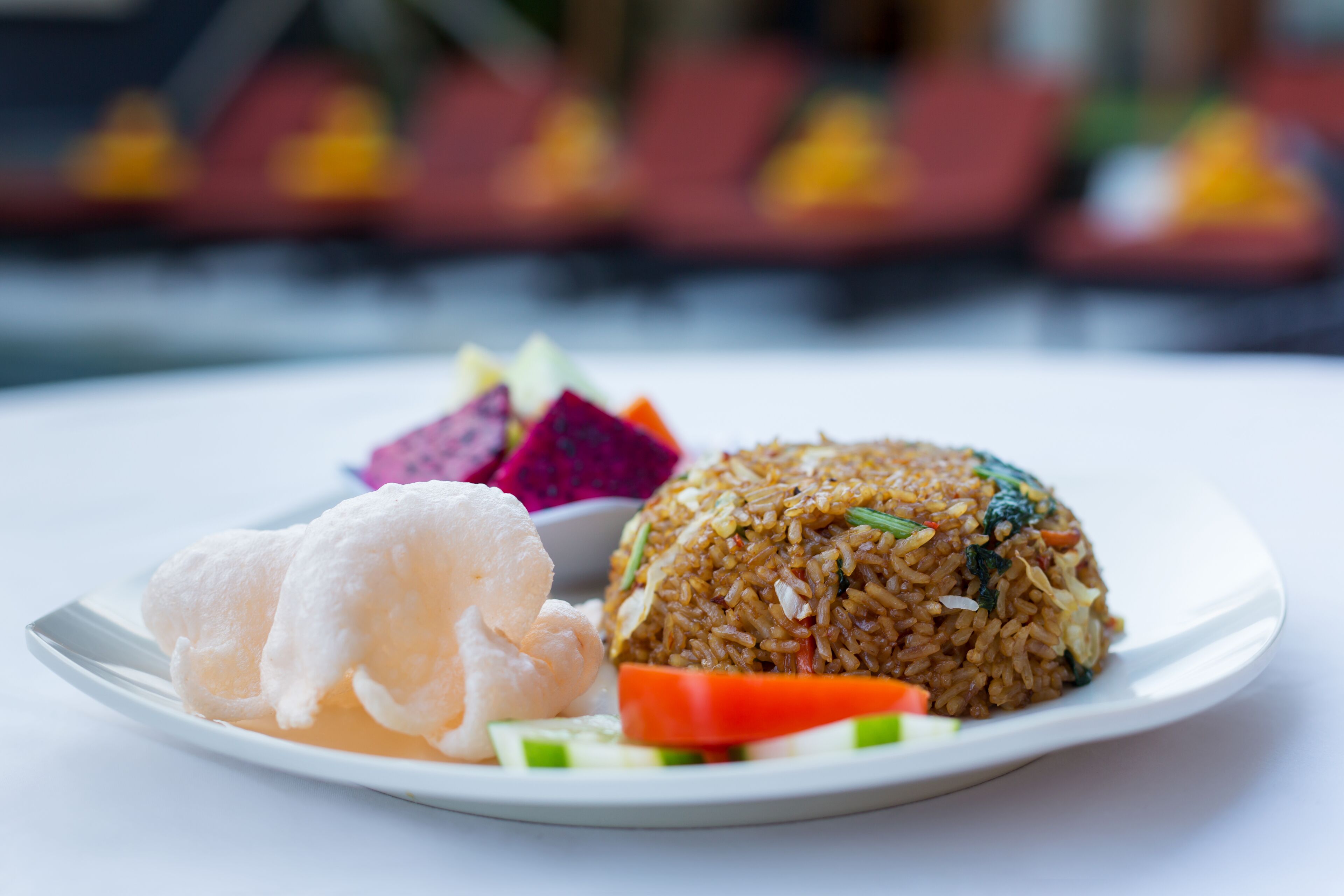 Un plato de arroz frito con verduras y un bollo de gambas.