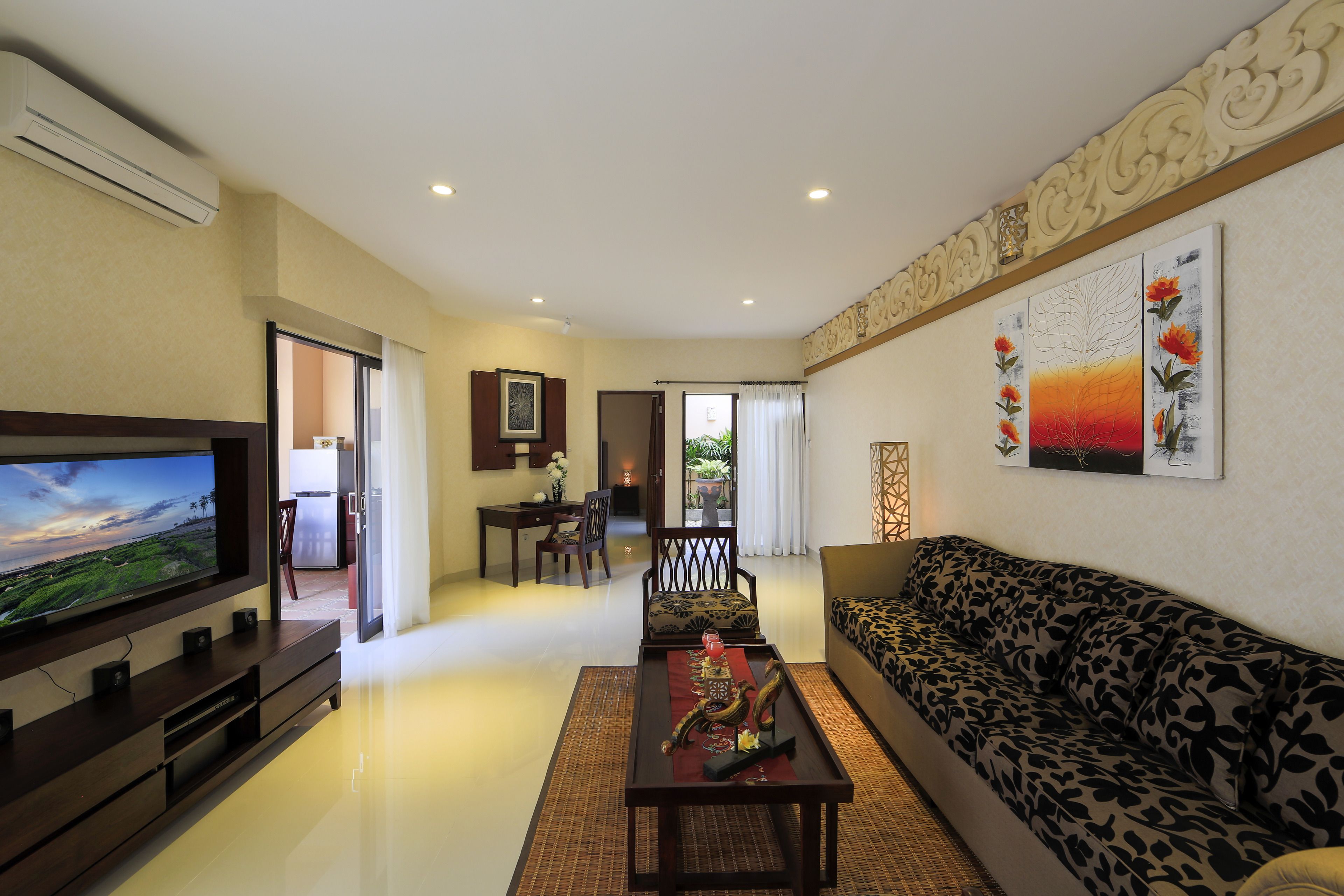 A modern living room with a flat-screen TV, a sofa, a coffee table, and a dining area with a chair and table.