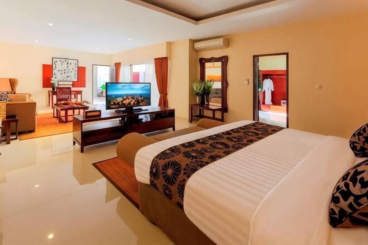 A modern hotel room with a large bed, a television, a desk, and a mirror.