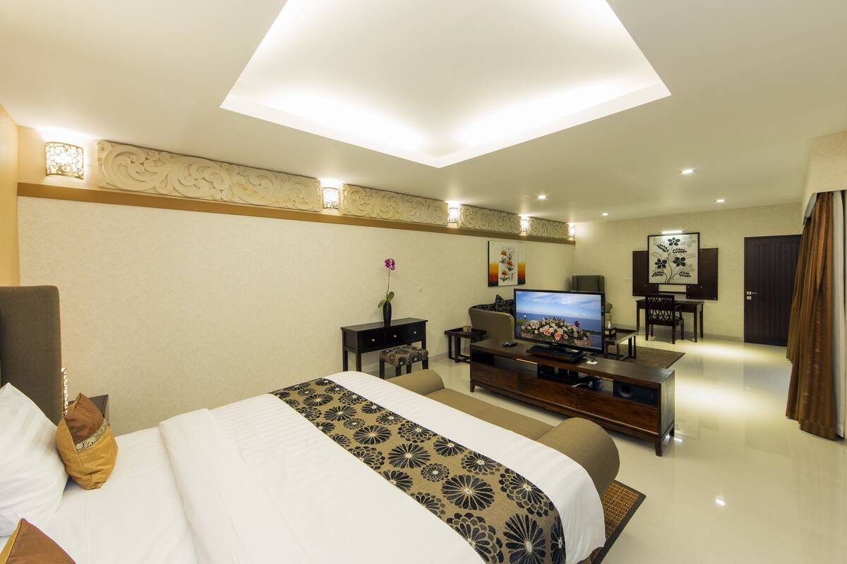 A hotel room with a large bed, a television, a desk, and a chair.