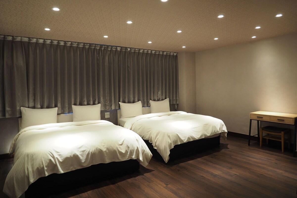 Habitación de hotel con dos camas, un escritorio y una silla.