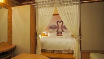 A bedroom with a bed, a wooden headboard, a nightstand, and a table.