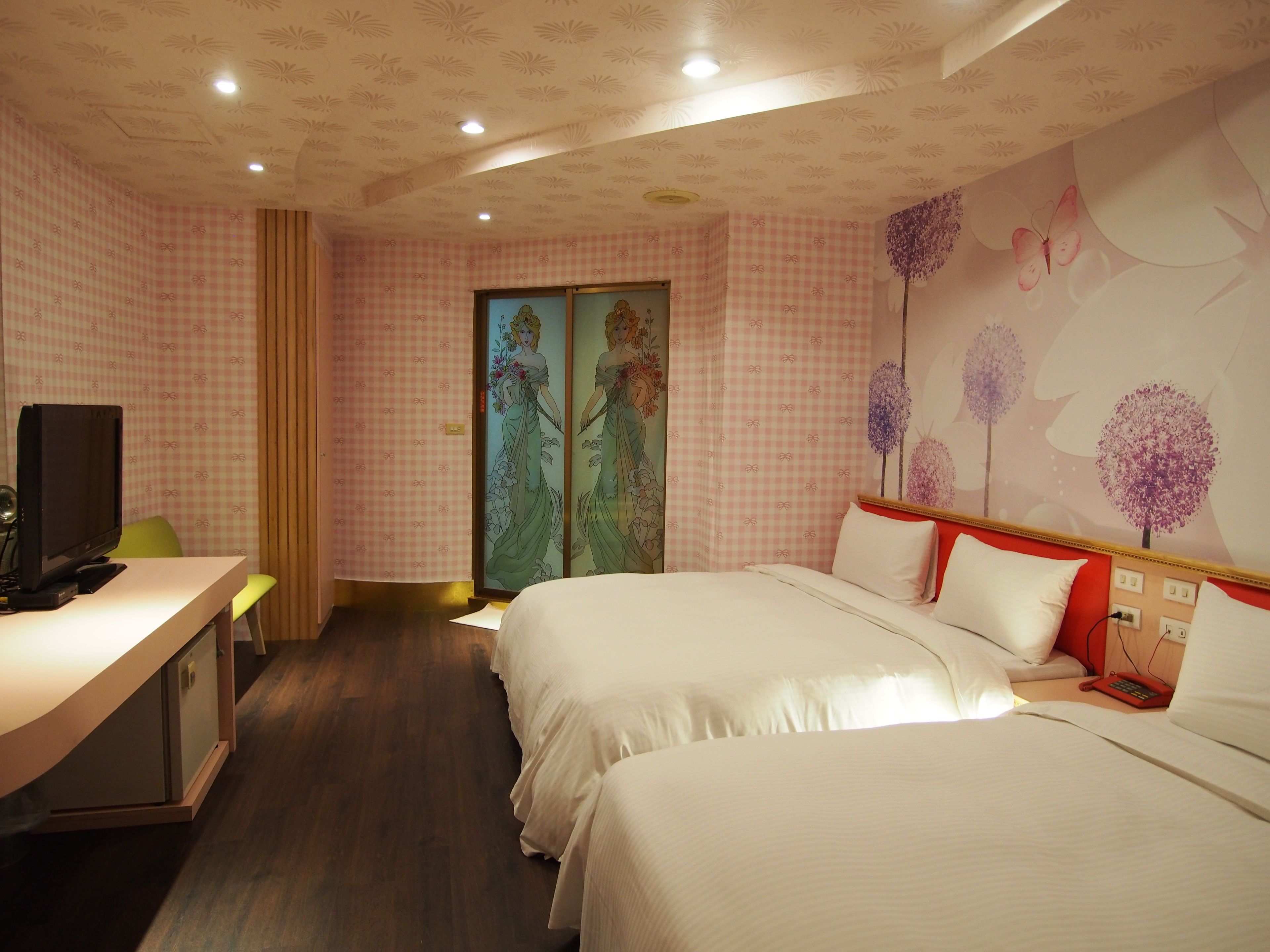 Habitación de hotel con dos camas, un escritorio con computadora y televisión.