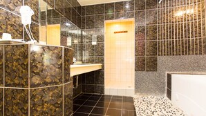 A bathroom with a black and gold tiled wall, a white sink, and a shower area. - Day Chen Hotel (Yilan)