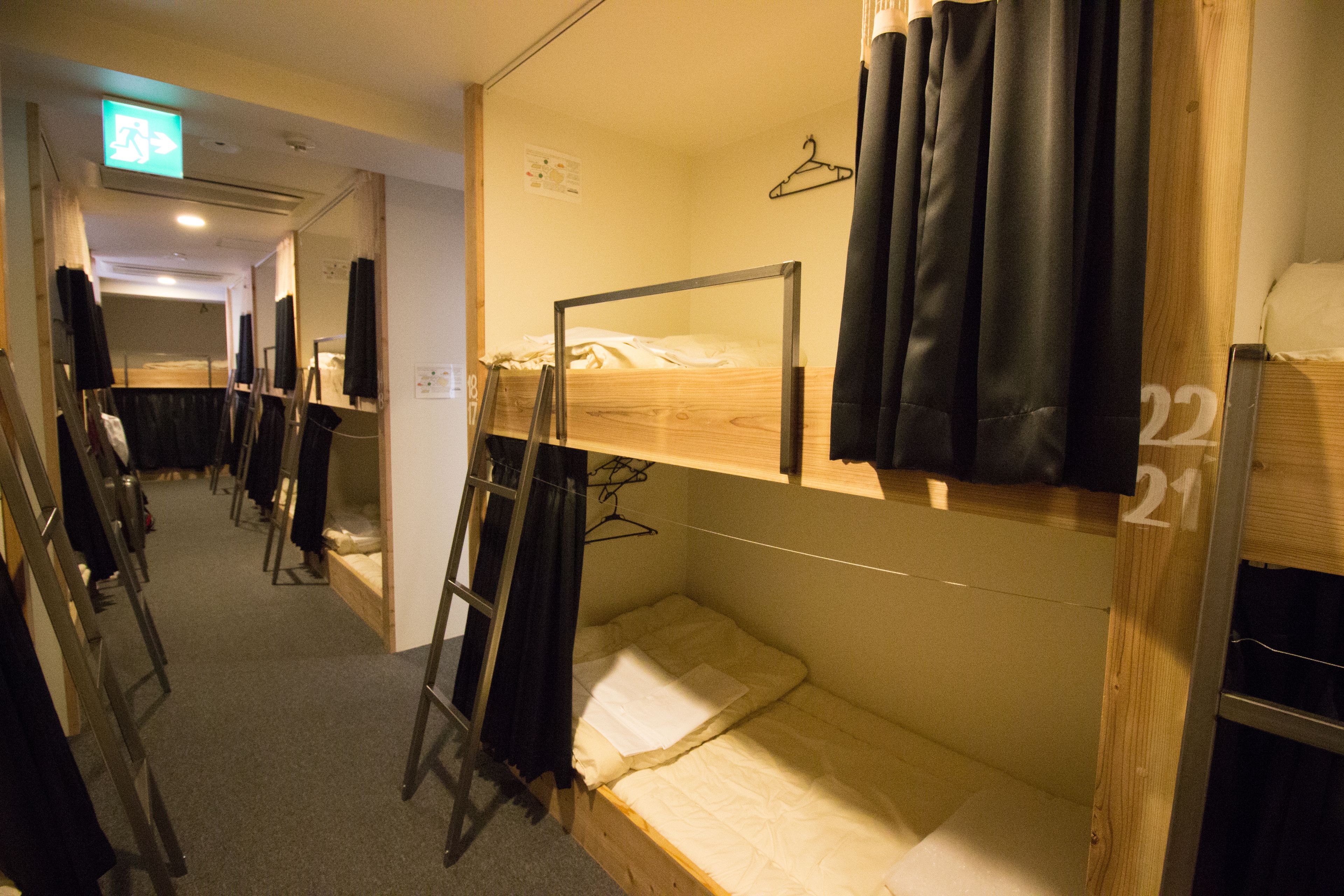 Un dormitorio con literas, una escalera de madera y un perchero en la pared.