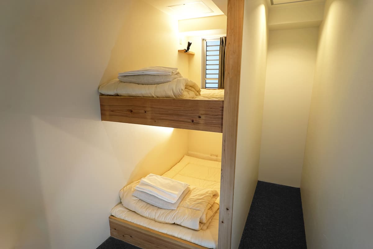 Una cama litera con cabecera de madera y un estante pequeño encima.