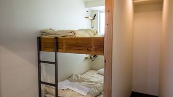 A bunk bed in a narrow room with a ladder, a window, and a ceiling vent.