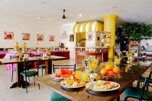 A dining area with tables set for breakfast, featuring plates of food, drinks, and a yellow-striped awning. - People Place Classic Hotel (Chiang Mai)