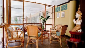 Una habitación con muebles de mimbre, una estatua y vistas a través de un ventanal.
