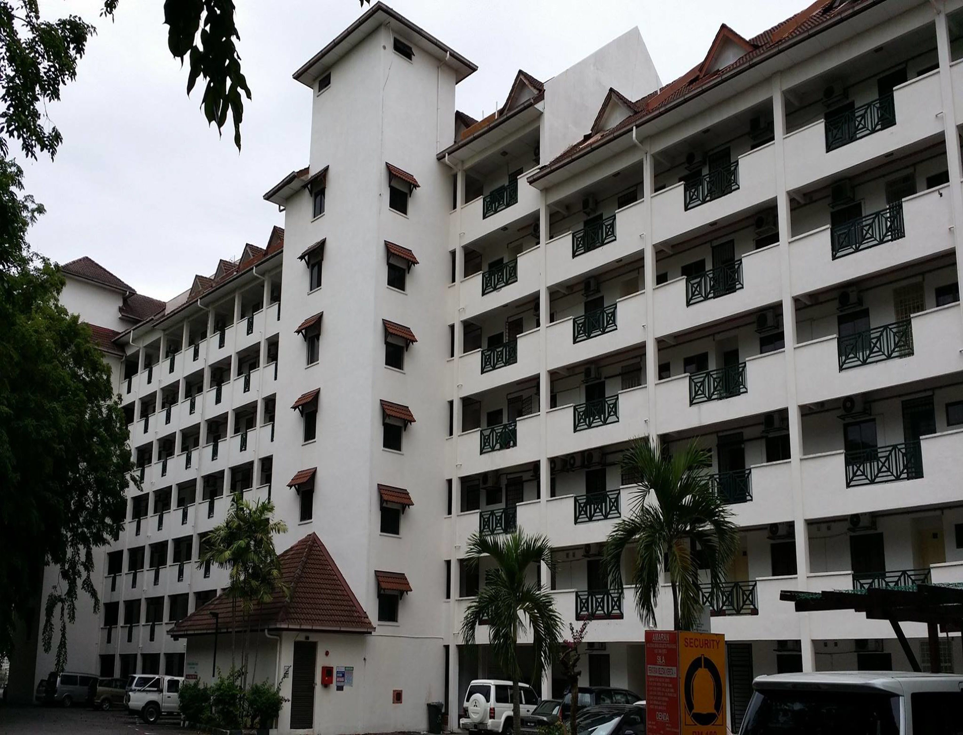 Ein mehrstöckiges Hotel mit einem zentralen Turm, Balkonen und einem Parkbereich.