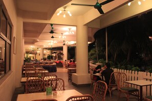 A restaurant with tables and chairs, a ceiling fan, and hanging lights. - Bayu Beach Resort (Port Dickson)