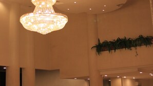 A grand chandelier hanging from the ceiling in a spacious lobby area with high ceilings and columns. - Bayu Beach Resort (Port Dickson)
