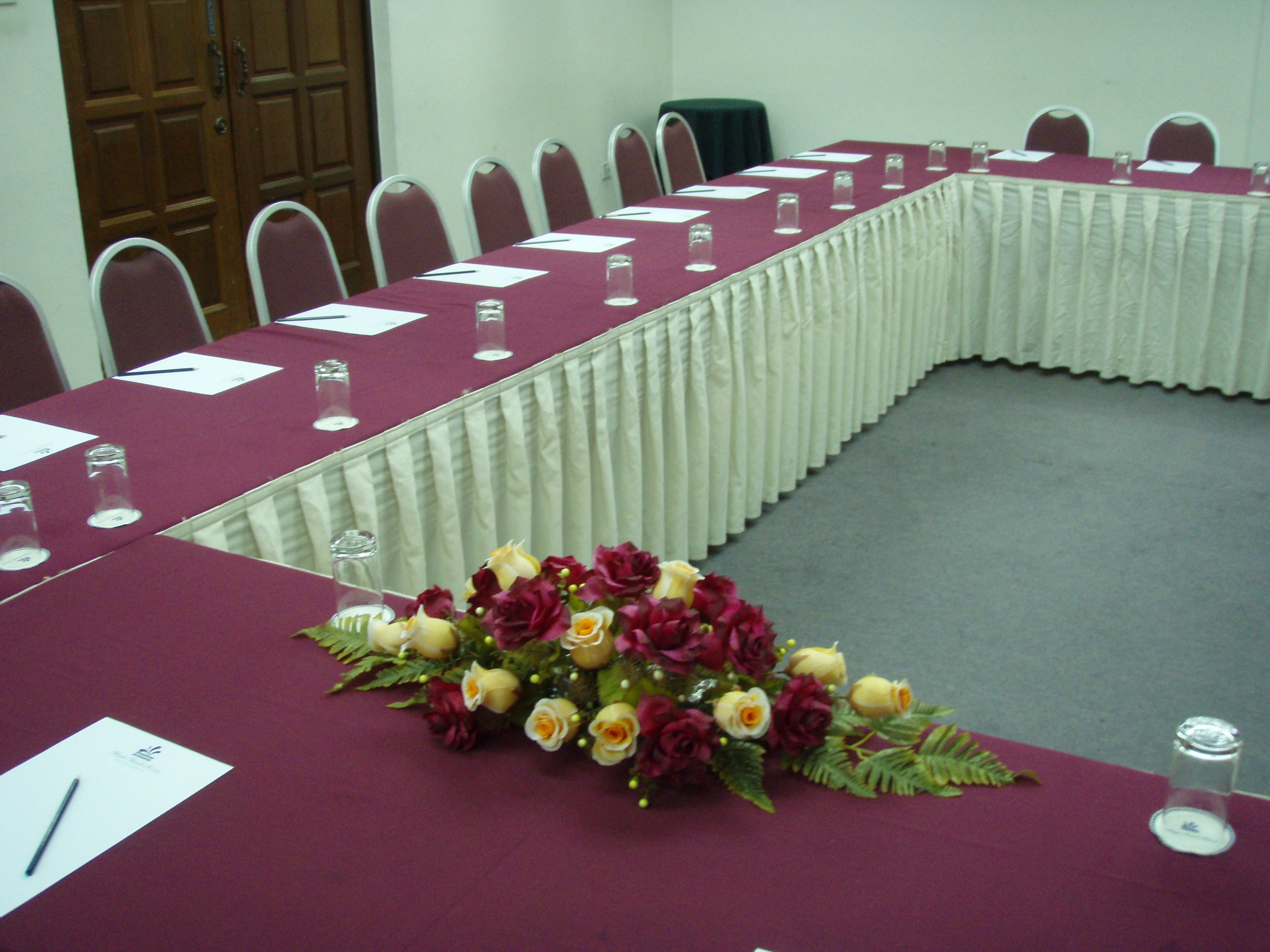 A conference room with a long table, chairs, and a floral centerpiece.