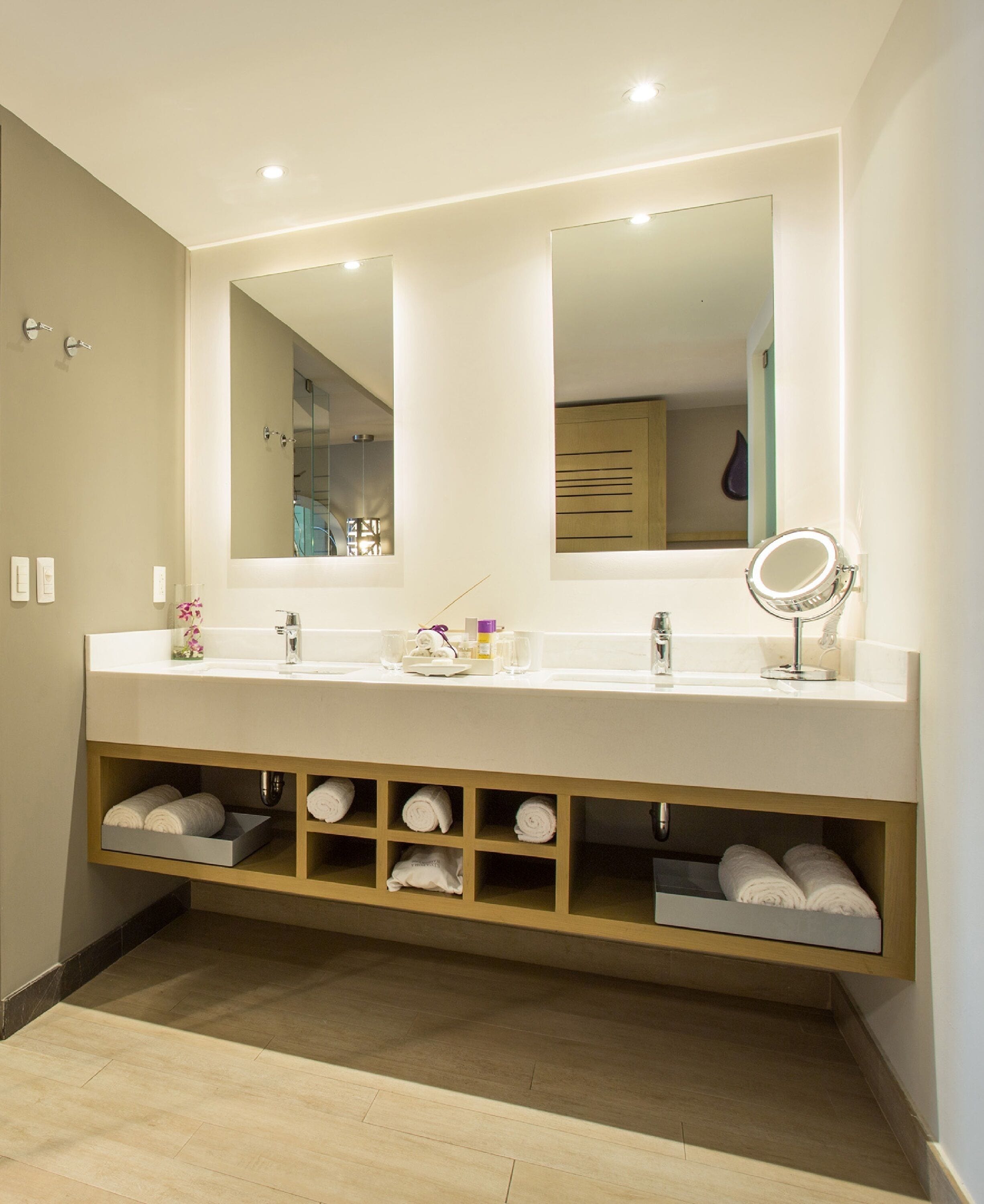 Un bagno moderno con un mobile doppio lavabo, portasci integrati e uno specchio grande sopra il mobile.