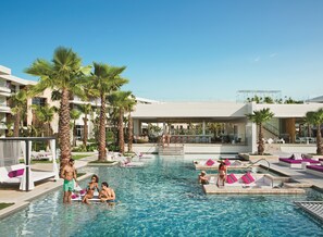A resort pool area with palm trees, lounge chairs, and a bar. - Breathless Riviera Cancun Resort & Spa - Adults Only - All Inclusive (Puerto Morelos)