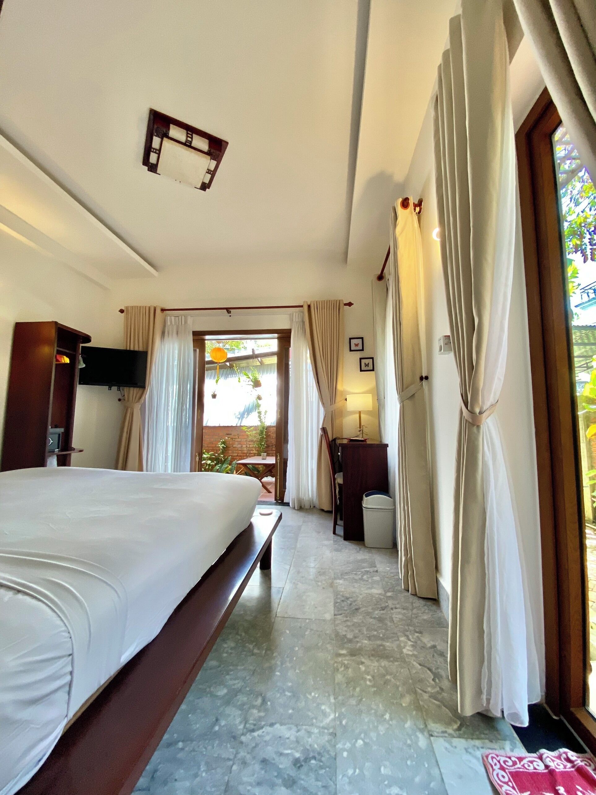A hotel room with a large bed, a desk, and a view of the outdoors.