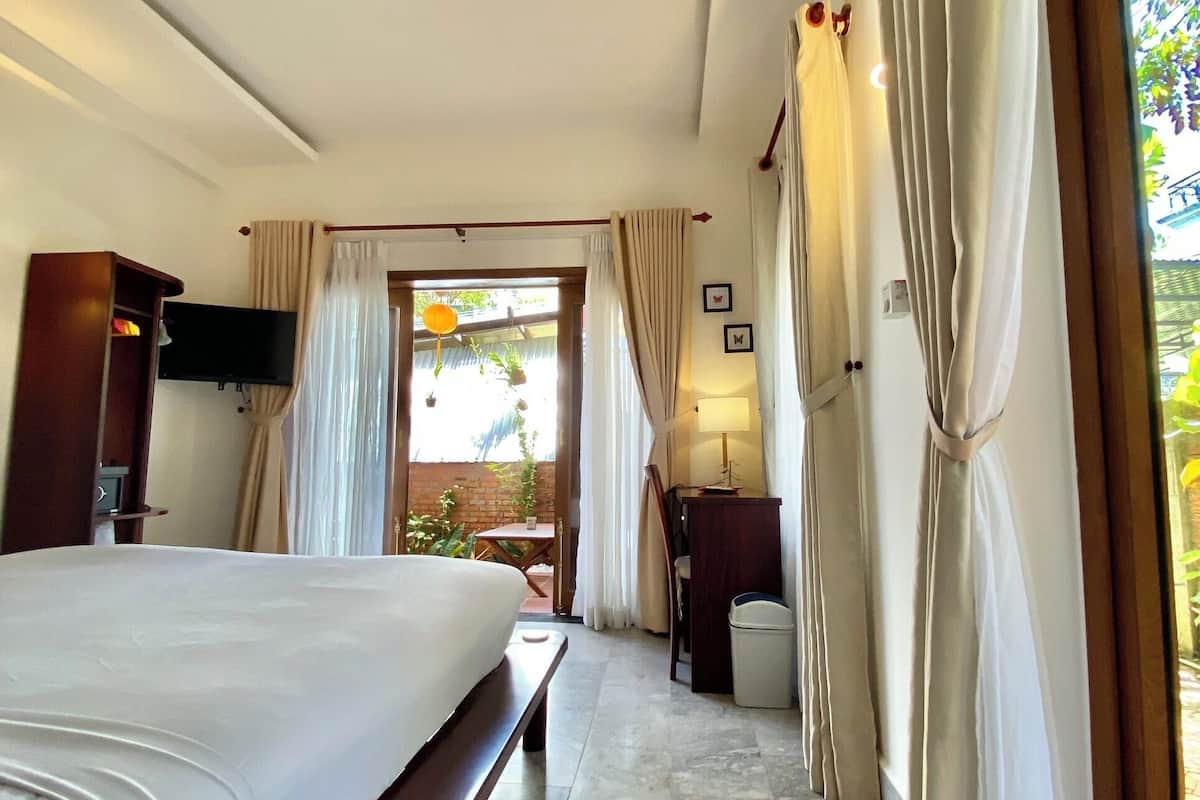 A hotel room with a large bed, a desk, and a view of the outdoors.