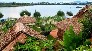 Cabanas com telhado de palha e vista para um lago e montanhas ao longe.