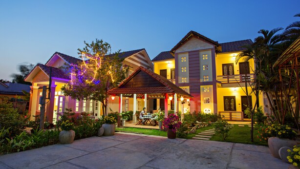 A two-story house with a covered patio and a well-maintained garden. - Do River Homestay (Da Nang)