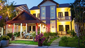 A two-story building with a covered patio and a well-maintained garden. - Do River Homestay (Da Nang)