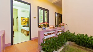 A hotel room with a bed, a bedside table with a vase of flowers, and a window with a view of the outside. - Do River Homestay (Da Nang)