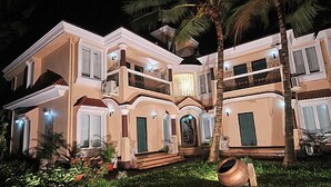 Una casa grande de varios pisos con fachada simétrica, varios balcones y una entrada bien iluminada.