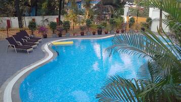 Relax by the pool surrounded by lush greenery and palm trees.