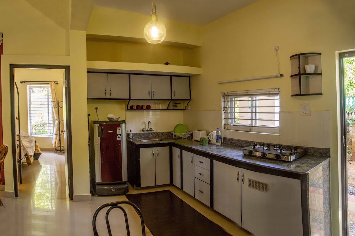 A kitchen with a refrigerator, stove, sink, and window.