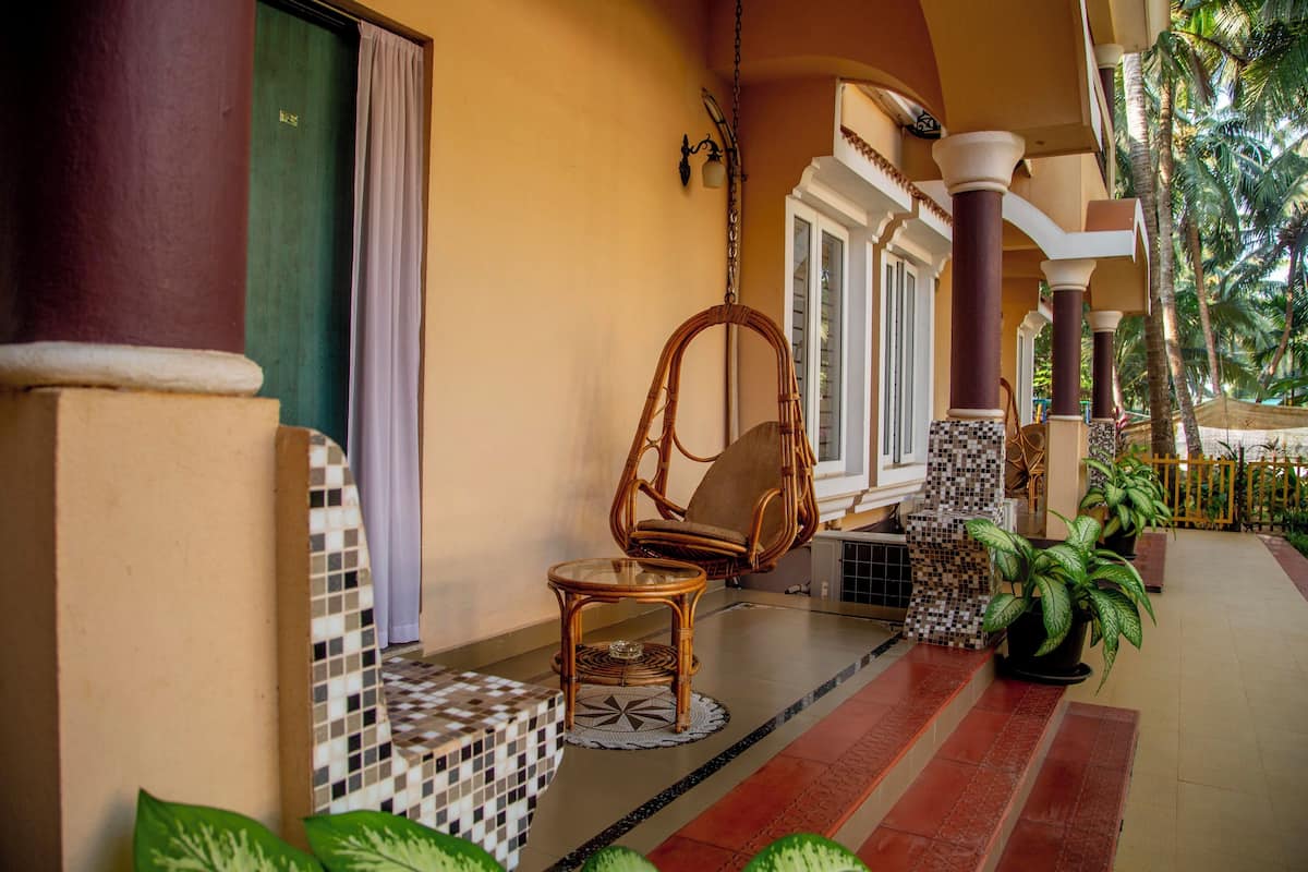 A covered outdoor area with a wicker chair, a small table, and potted plants.