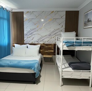A bedroom with a bed, a bunk bed, a wooden headboard, a marble-patterned wall, and a framed picture. - Perth City Motel (Thornlie)