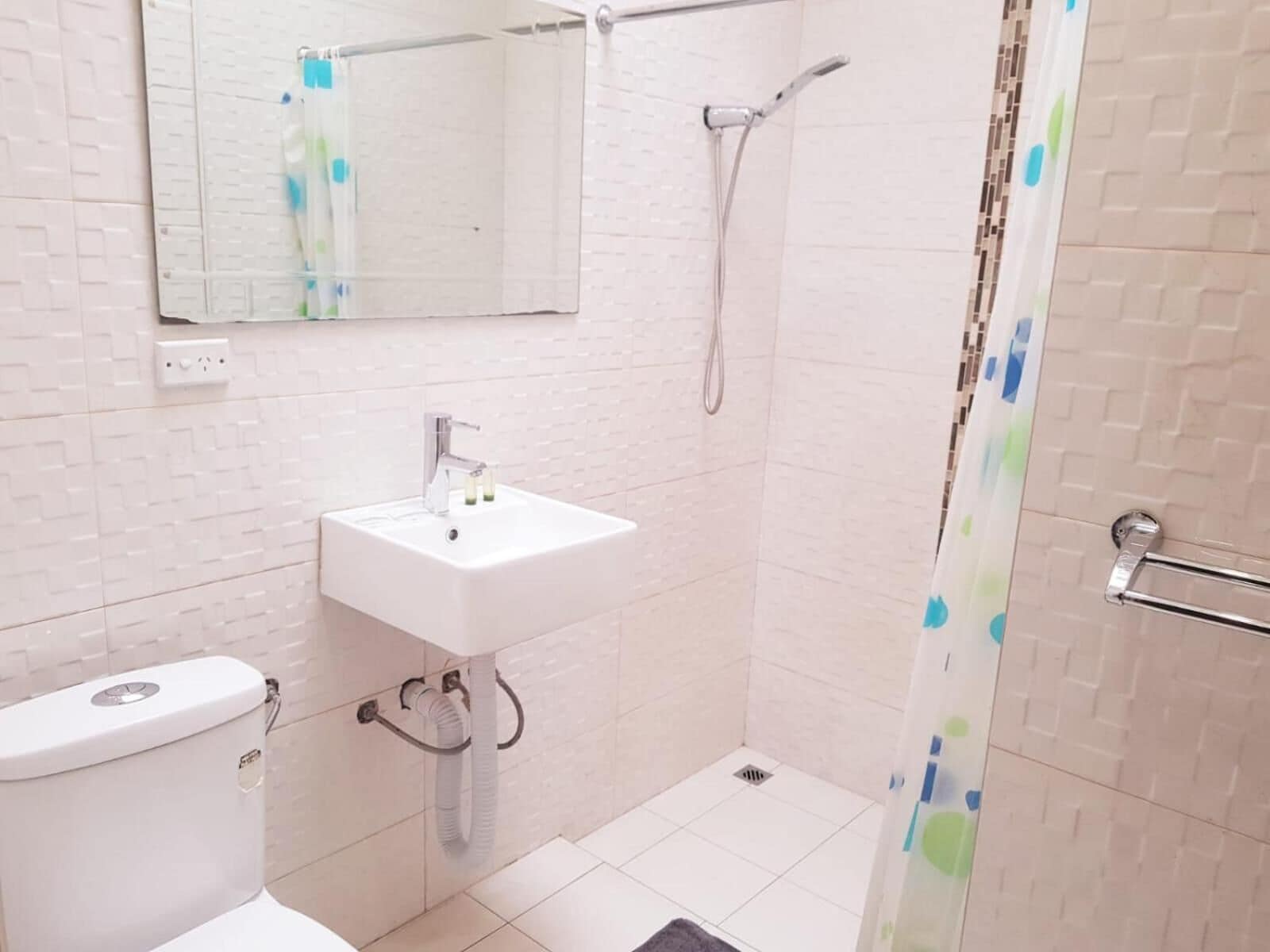 Une salle de bain équipée de toilettes, d’un lavabo, d’une douche et d’un miroir.