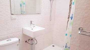 Une salle de bain équipée de toilettes, d’un lavabo, d’une douche et d’un miroir.