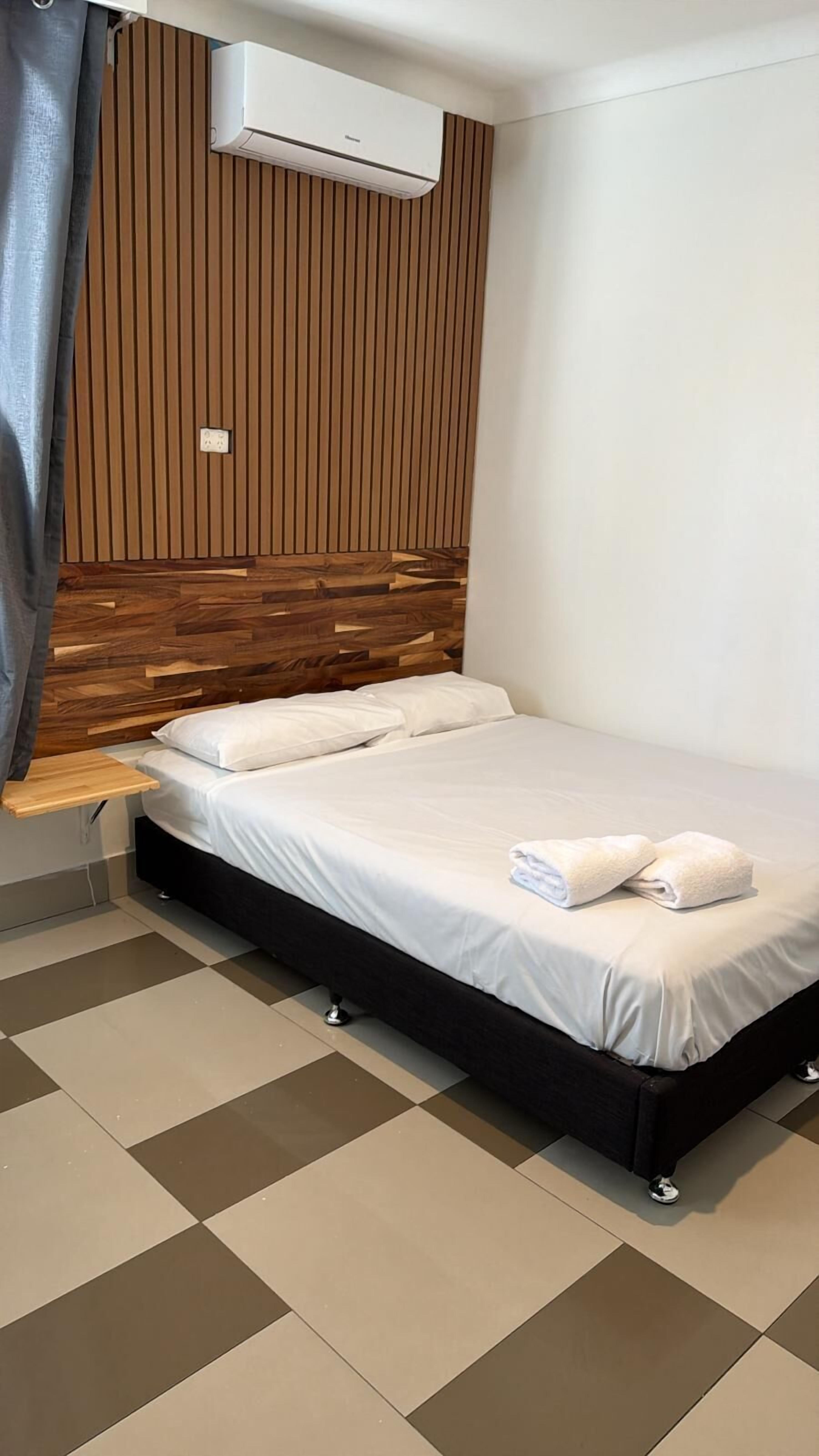 Un dormitorio moderno con cabecera de madera, cama con ropa de cama blanca y suelo a cuadros.