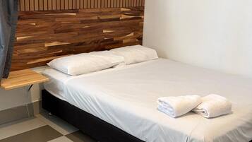 Un dormitorio moderno con cabecera de madera, cama con ropa de cama blanca y suelo a cuadros.