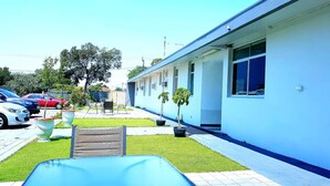 A building with a blue exterior, a paved patio with a pool table, and several potted plants. - Perth City Motel (Thornlie)