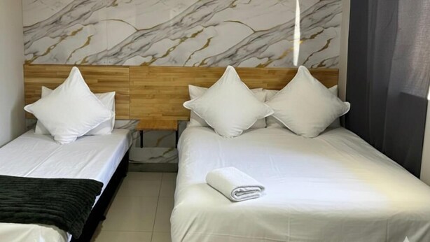 A hotel room with two beds, marble-patterned headboard, and a wooden panel above the beds. - Perth City Motel (Thornlie)