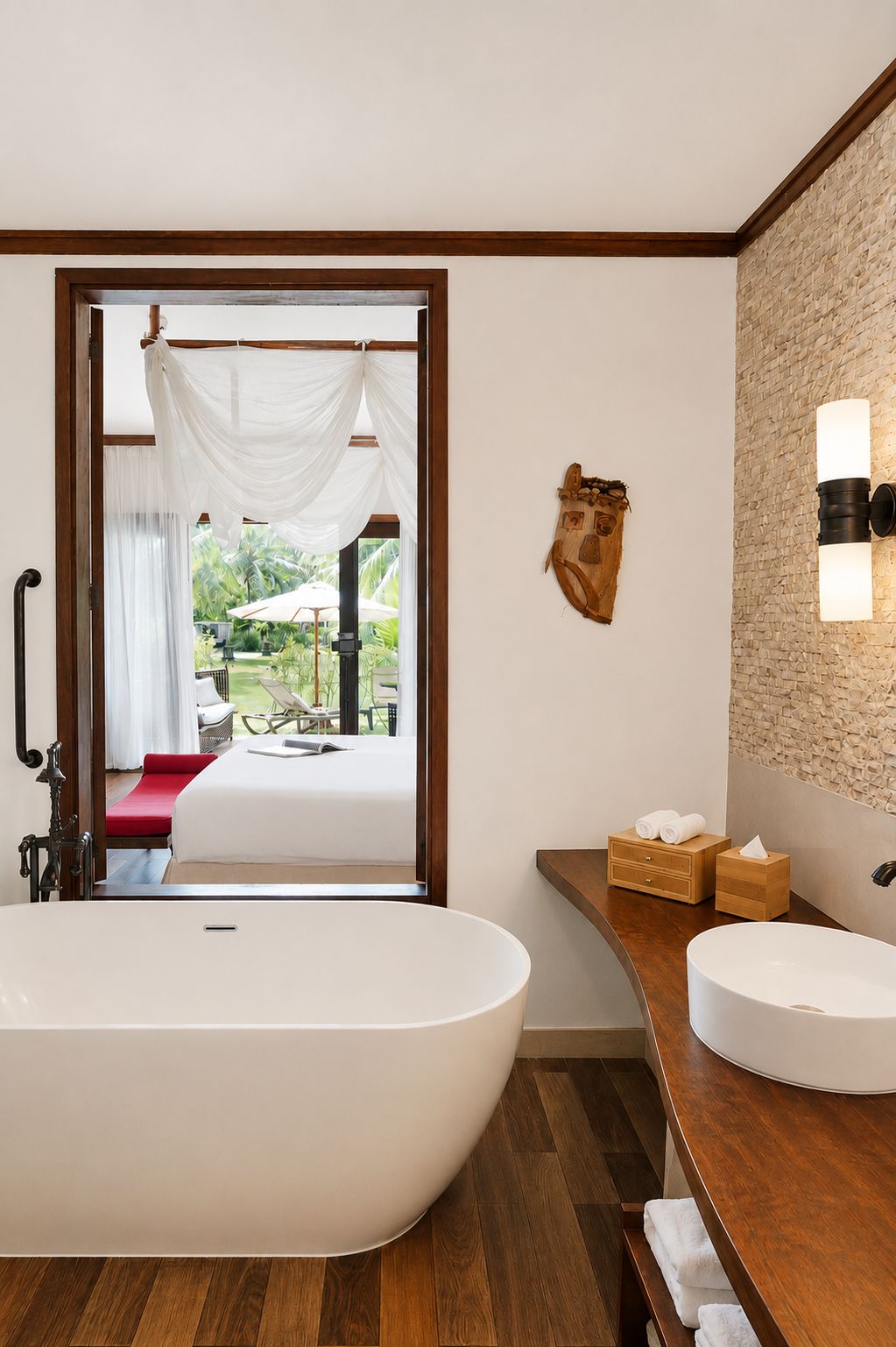 Un baño moderno con una bañera independiente, un tocador de madera y vistas a una zona de estar al aire libre.