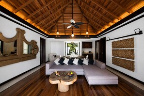 Un salón amplio con techo alto, un sofá grande, una mesa de centro de madera y un adorno en la pared.