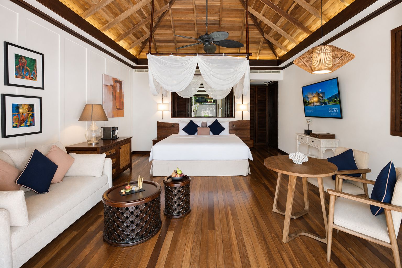 A hotel room with a bed, a sofa, a round wooden table, and a TV.