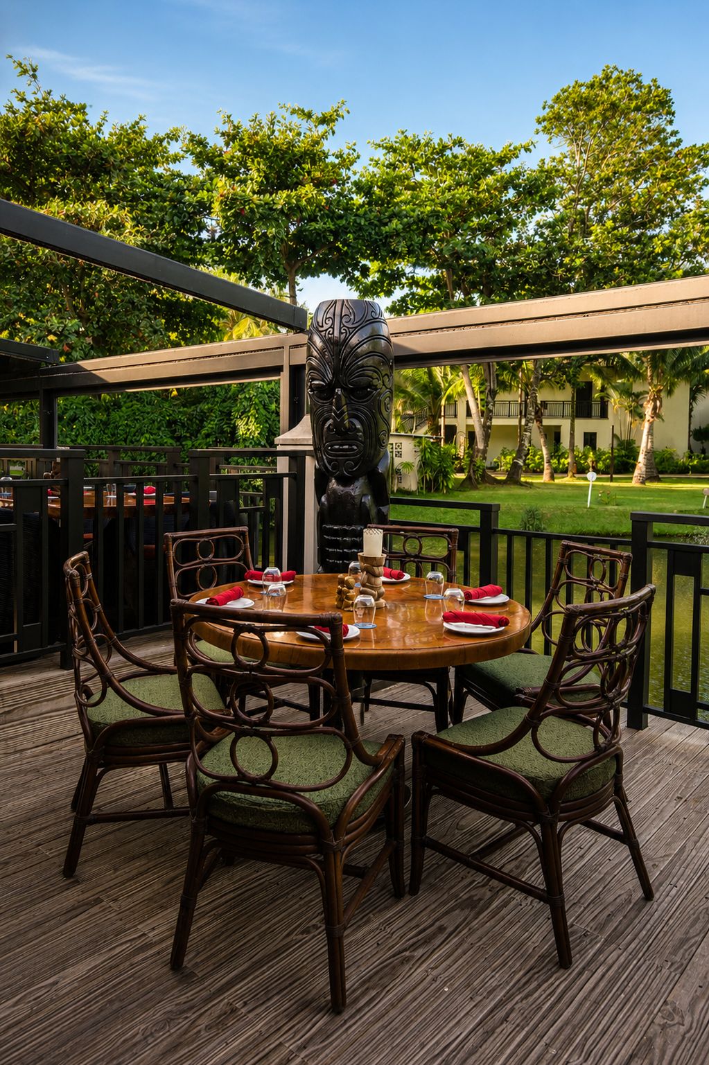 A wooden deck with a round table set for dining, surrounded by wicker chairs.