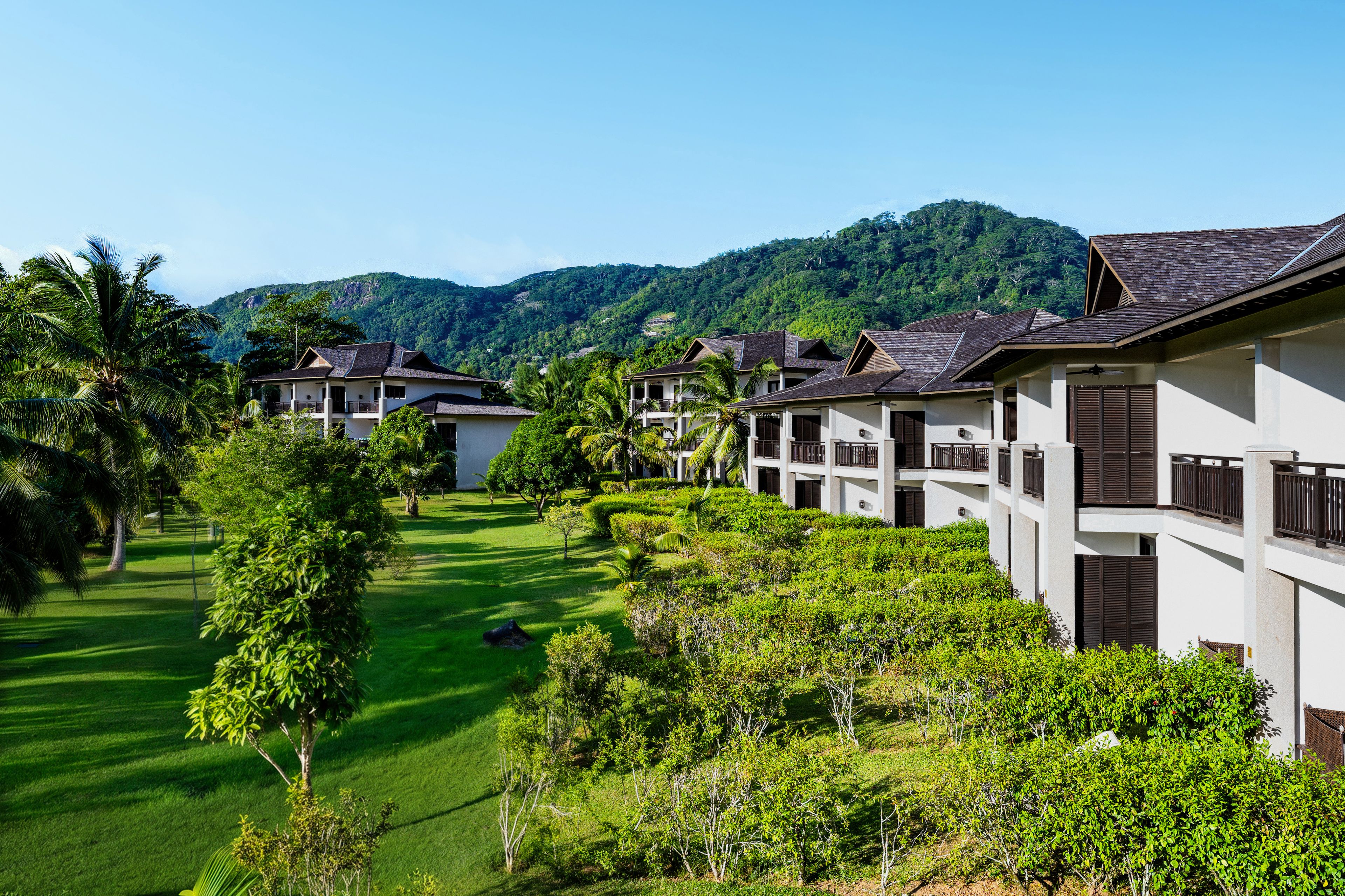 A resort with multiple-story buildings, lush green lawns, and tropical vegetation.