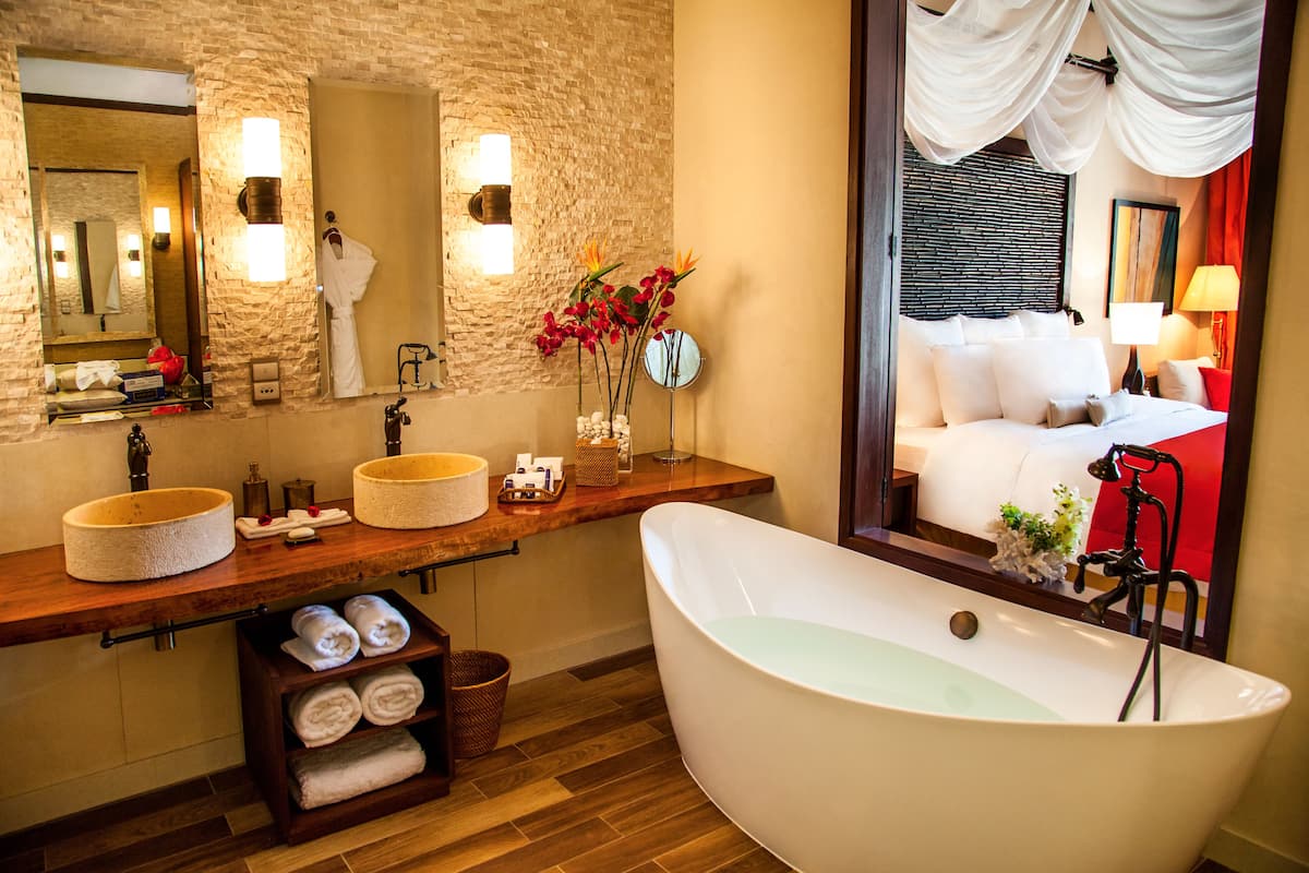 A modern bathroom with a freestanding bathtub, a large mirror, and a wooden vanity with two sinks.